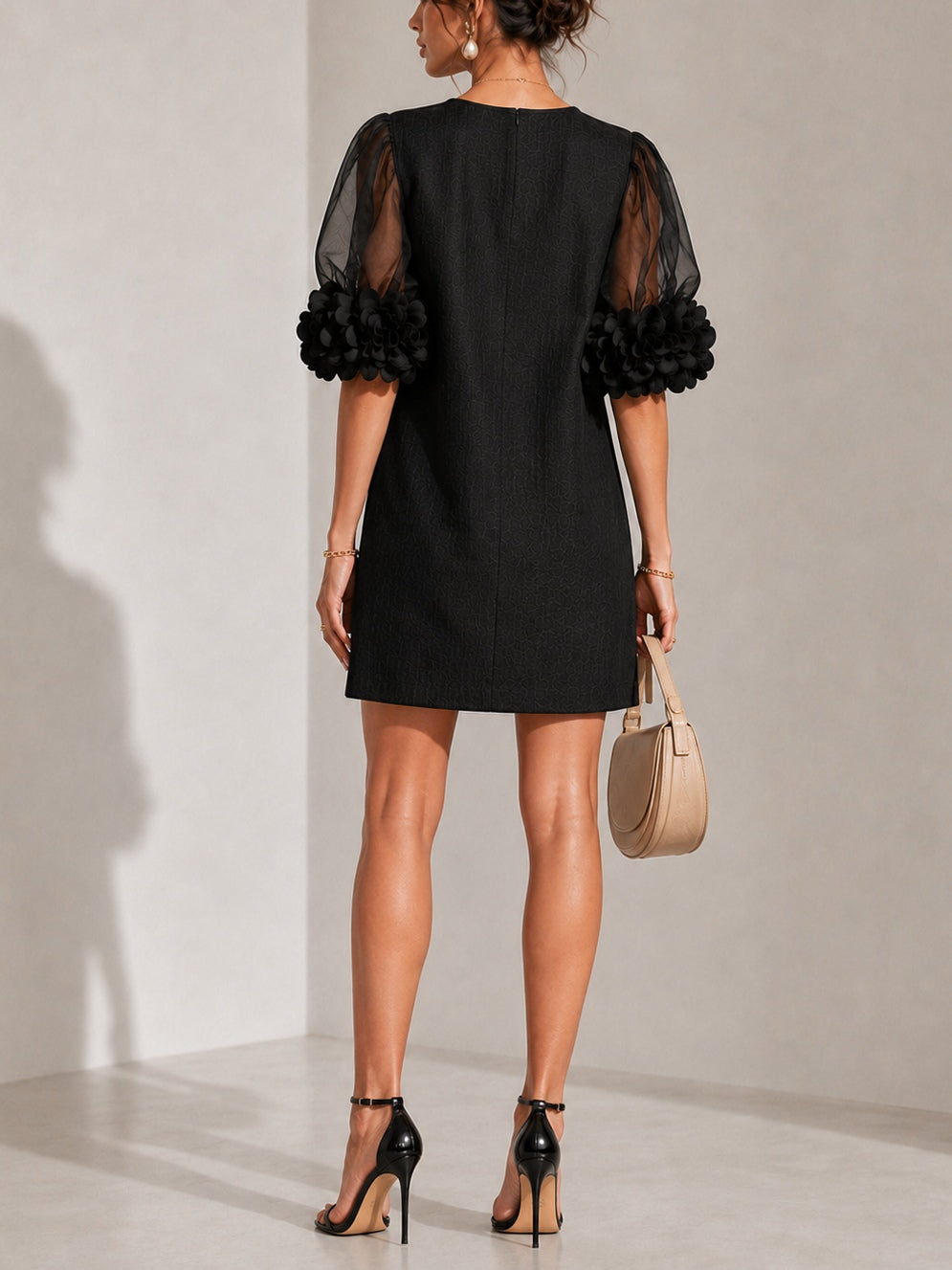Black dress with sheer puff sleeves and floral appliqué detail, back view