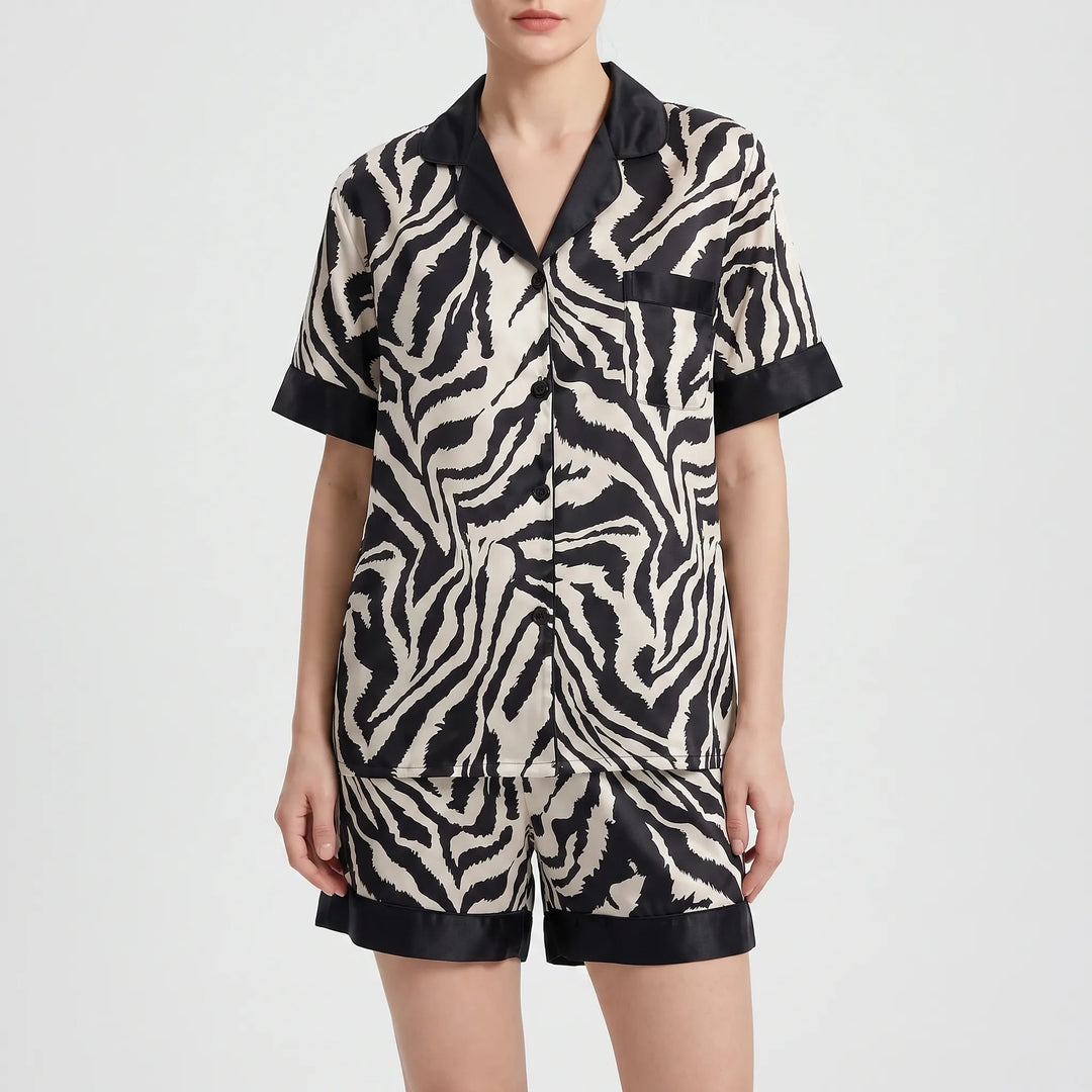 Front view of a model wearing the short-sleeve zebra-print satin pajama set with matching shorts and black trim at sleeves and hems. 5