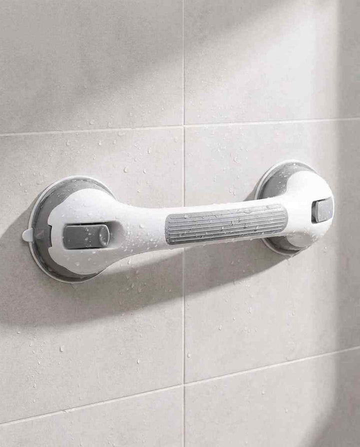 Grab bar with ribbed gray grip mounted horizontally on beige tile with water droplets.