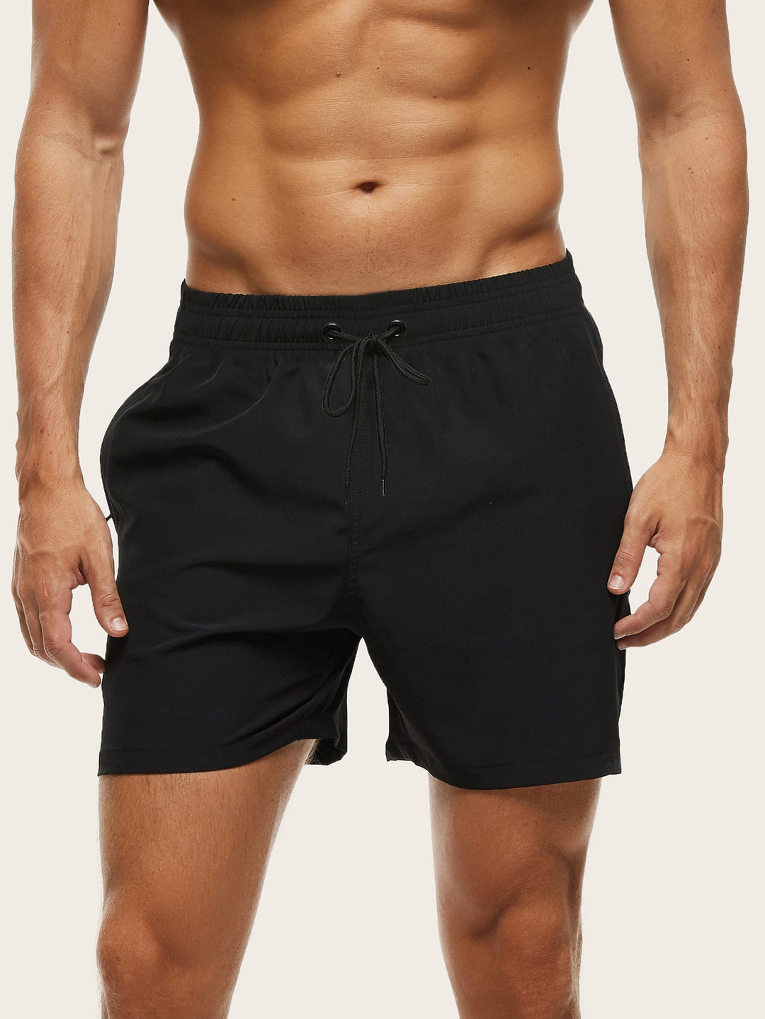 Men's swim trunks in black on a model, front view with a black drawstring and elastic waistband.