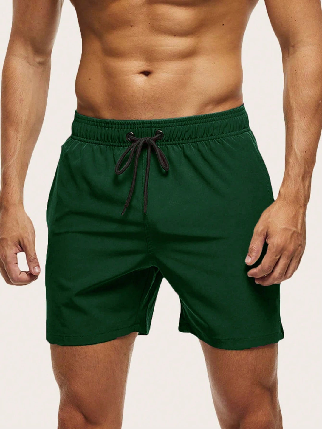Men's swim trunks in dark green on a model, front view with black drawstring and short straight legs.