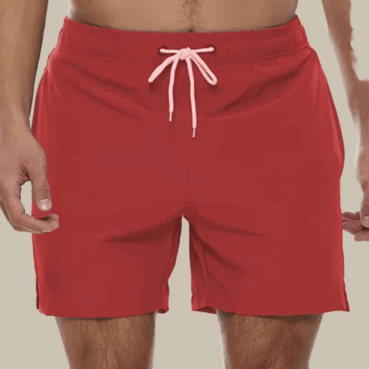 Red swim trunks with a pale pink drawstring and side hem slits, front view.