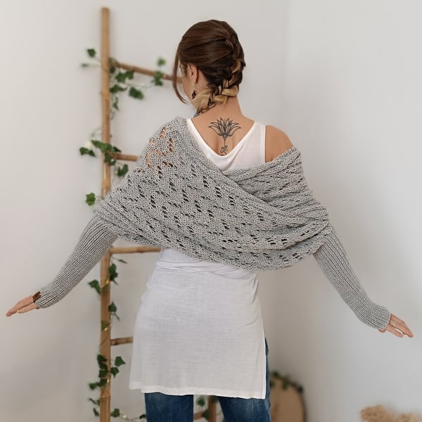 Back view of the light gray wrap with arms outstretched, showing the lace panel draped across the shoulders and long ribbed sleeves. 9