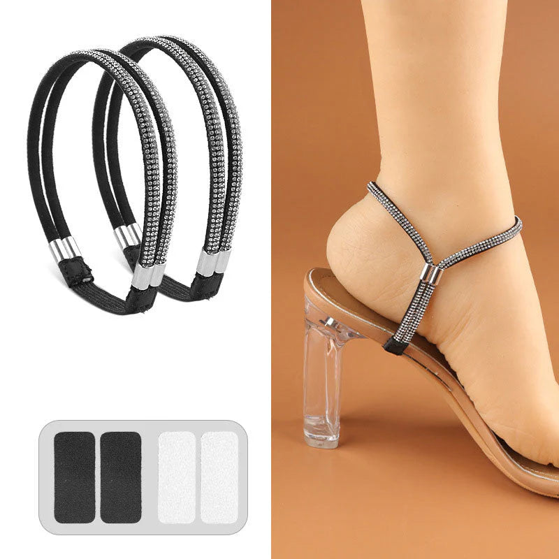 Pair of black elastic shoe straps with sparkling crystal rows and adhesive pads secured around a heel in a clear-heeled sandal.