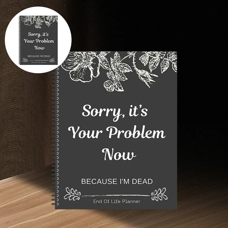 Spiral-bound planner with a dark charcoal cover and white floral line art, standing on a wooden shelf 10