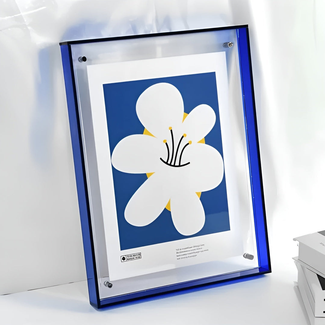 Blue-edged acrylic frame leaning on a white surface beside books.