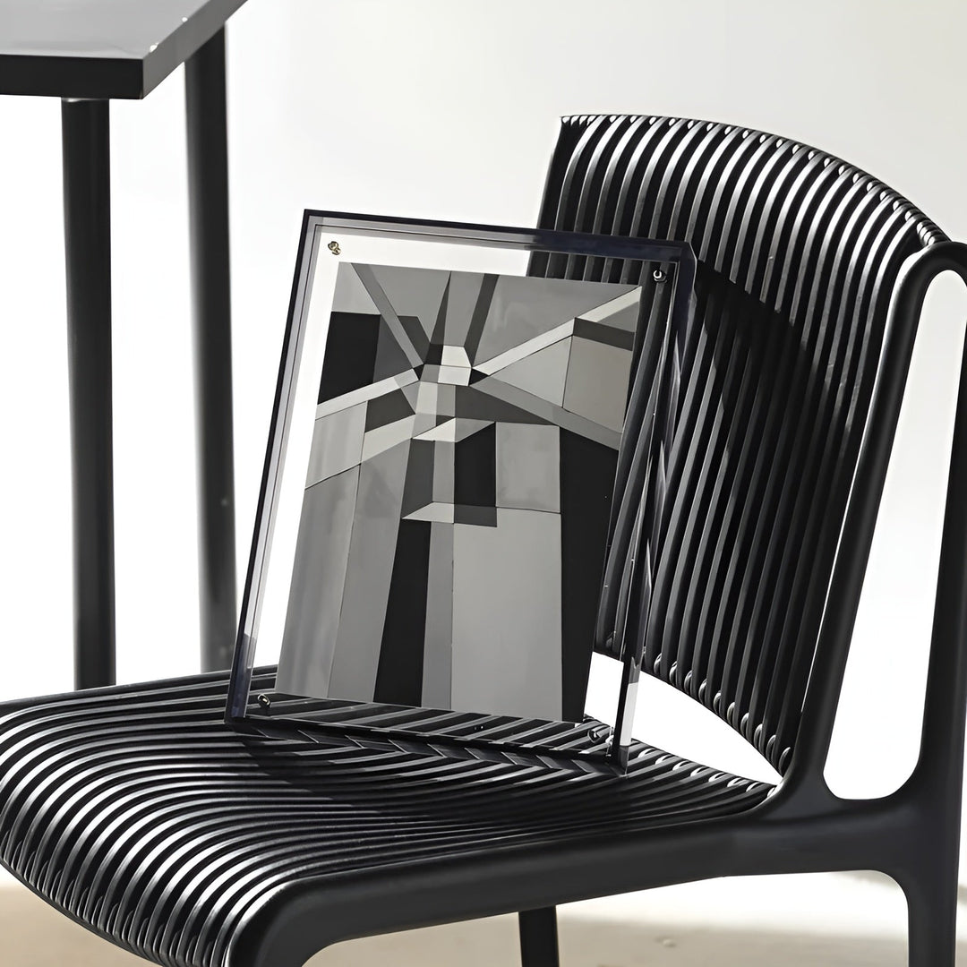 Clear acrylic frame with dark edges resting on a black slatted chair.