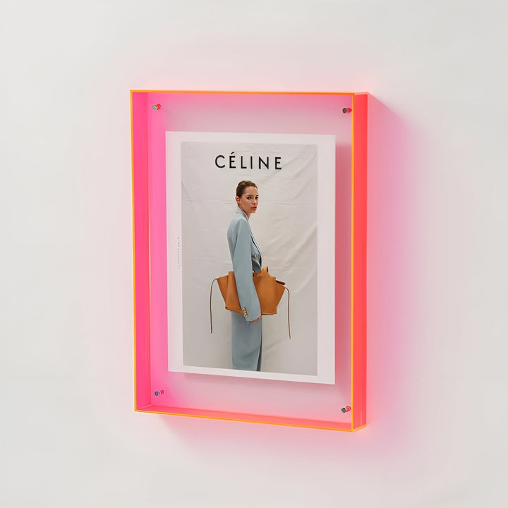 Neon pink and orange acrylic frame mounted on a white wall, glowing softly.