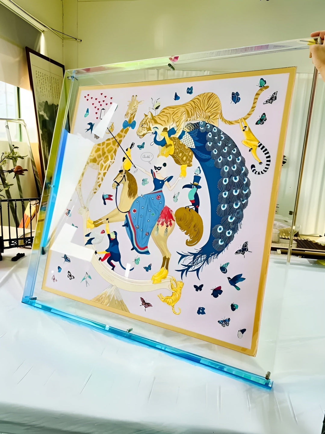 Large clear acrylic frame with a blue base edge held upright on a white table.