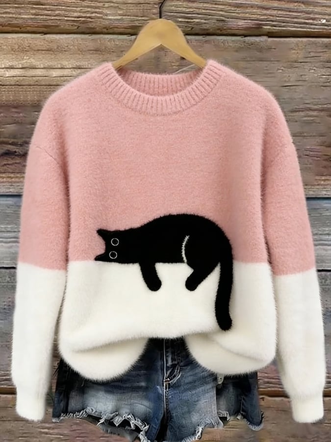 Pink and white fuzzy colorblock sweater with a black cat lying across the middle, shown on a hanger against wood planks. 3