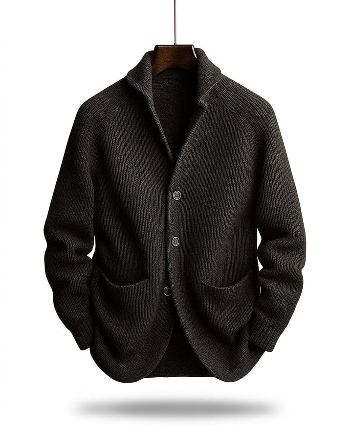 Charcoal black version of the ribbed cardigan hanging on a wooden hanger above a soft shadow 2