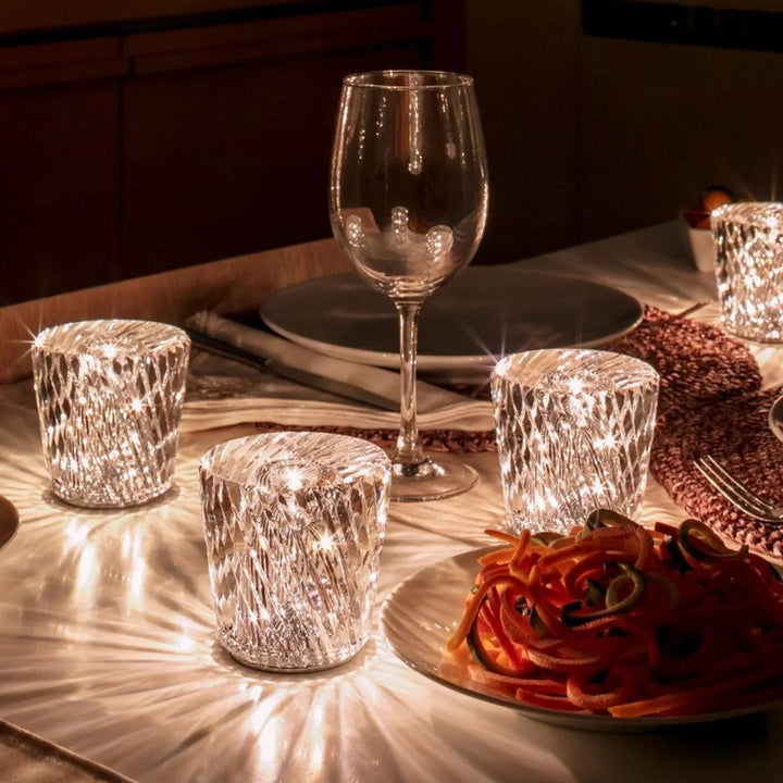 Gold transparent crystal table lamp, another view, on a set dinner table with plates and a wine glass.