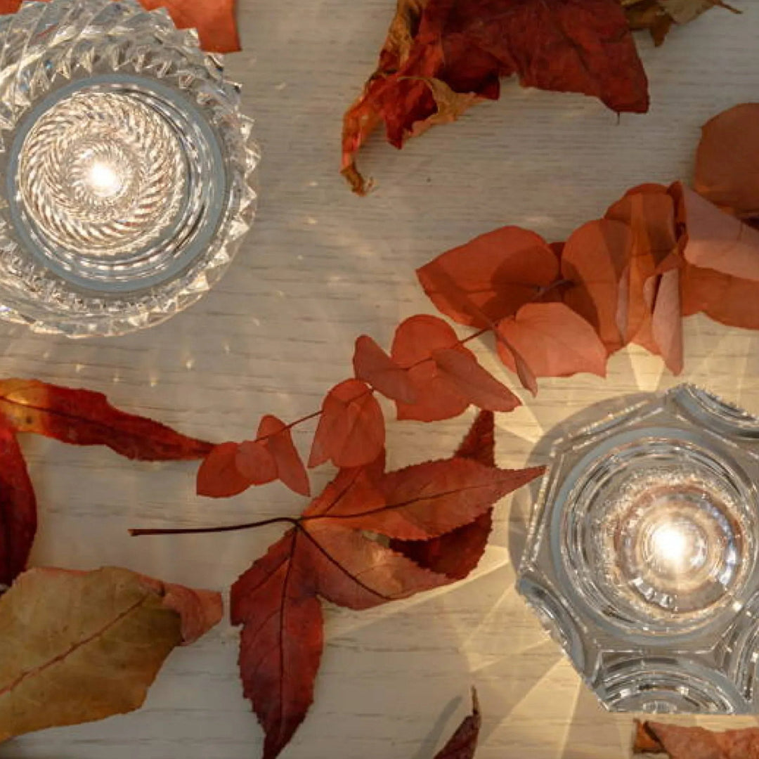 Gold transparent crystal table lamp, another view, on a light wooden table with dried red leaves.