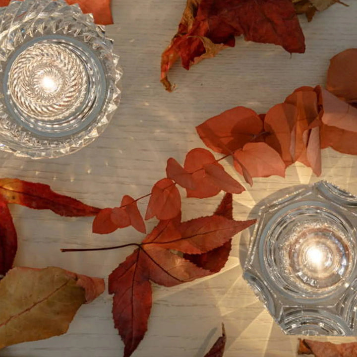 Gold transparent crystal table lamp, another view, on a light wooden table with dried red leaves.