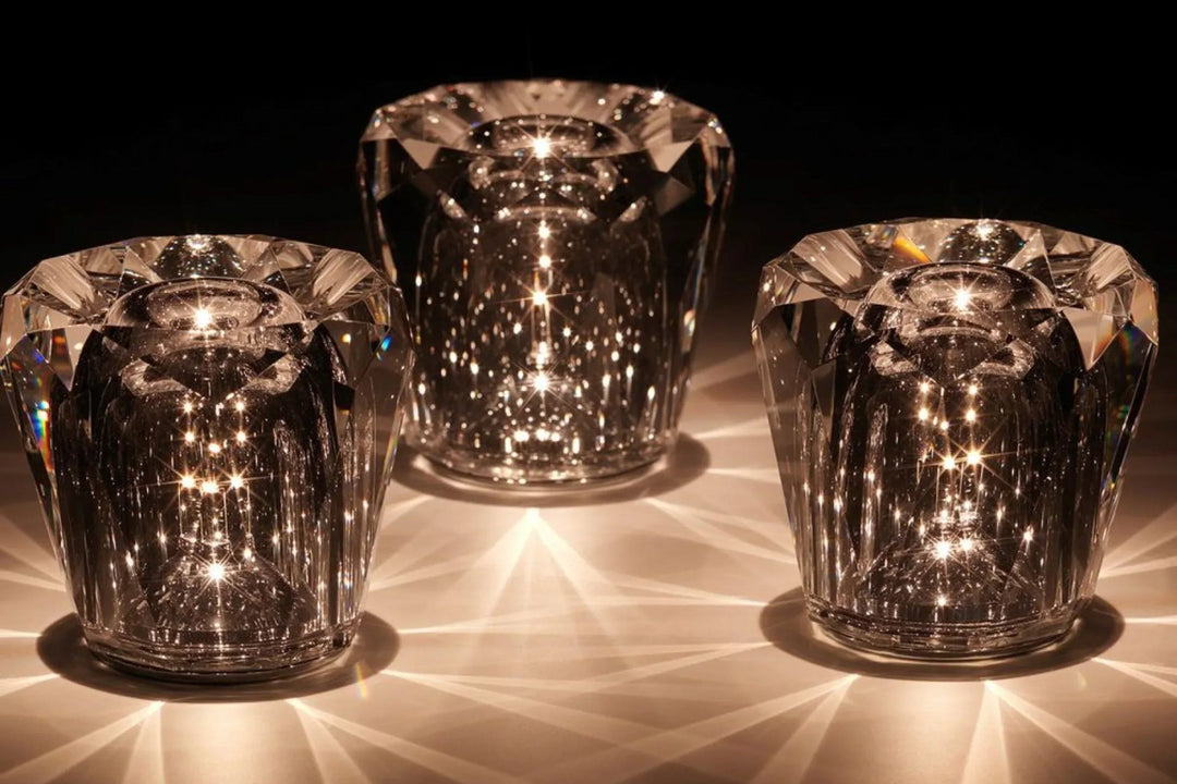 Gold transparent crystal table lamp with diamond-cut top, lit on a dark surface.