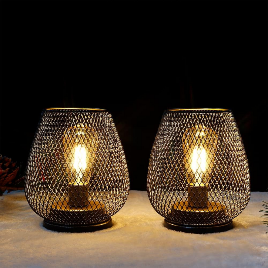 Pair of glowing mesh lanterns with amber-tinted bulbs on a soft white surface against a black background. 11