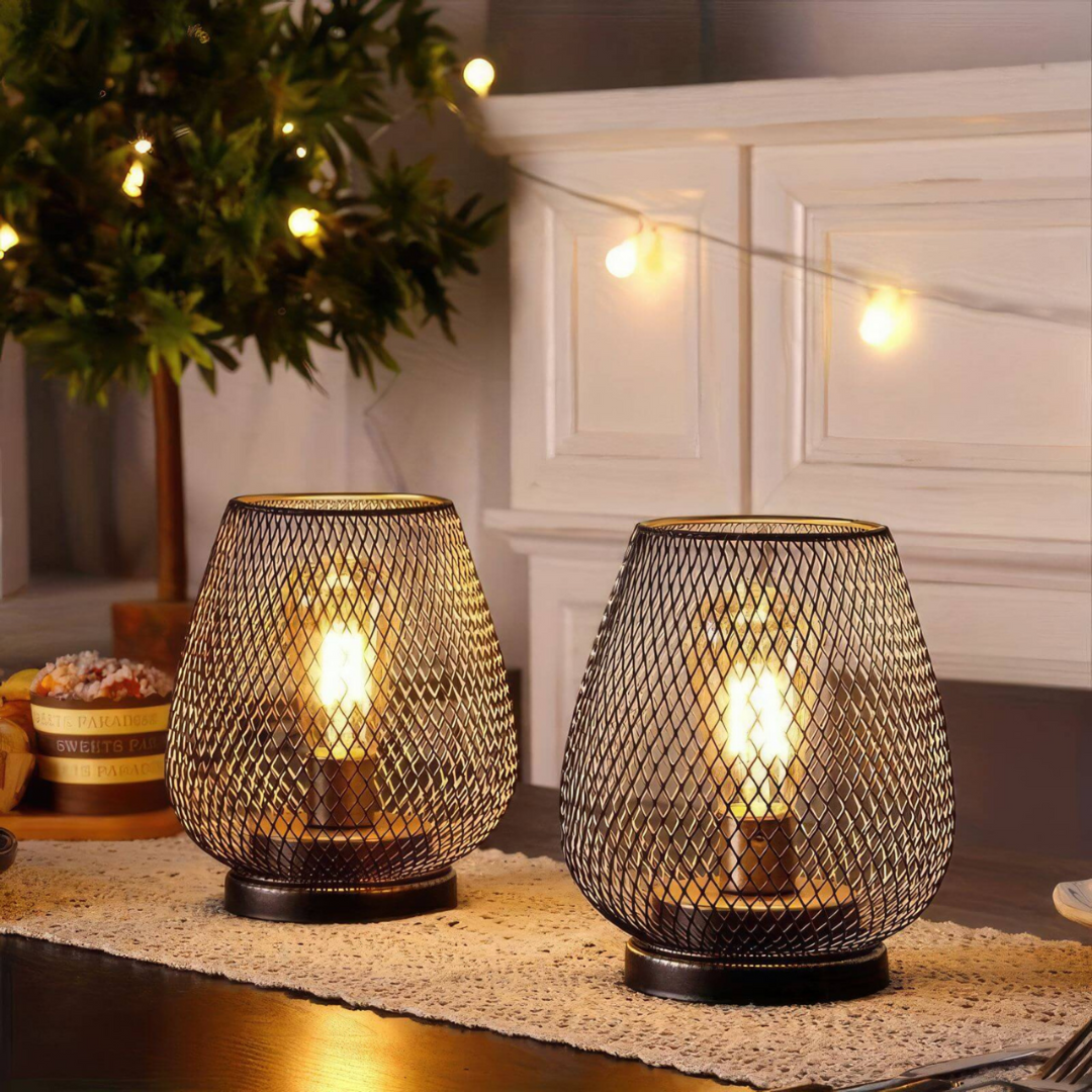 Pair of lit mesh lanterns on a lace runner beside a decorated green tree and a string of warm lights. 6