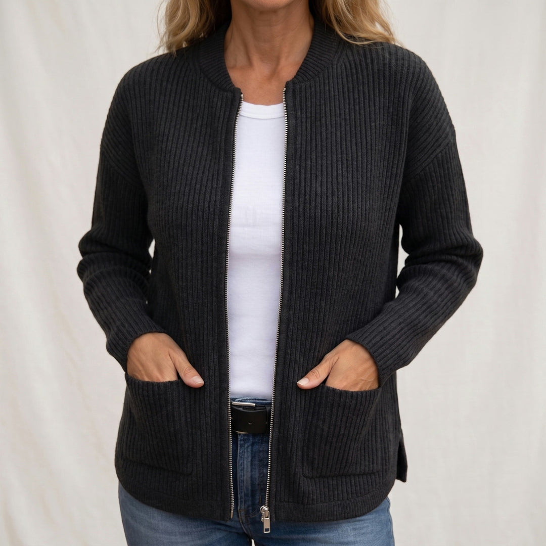 Woman wearing the ribbed zip-up cardigan in charcoal black, open over a white tee with jeans, hands resting in the front pockets. 2