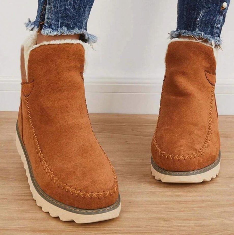 Tan brown slip-on ankle boots with contrast stitching and soft white lining at the ankle opening, front view.