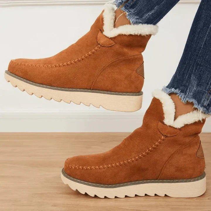 Tan brown slip-on ankle boots with fluffy white lining and cream treaded soles, side view.