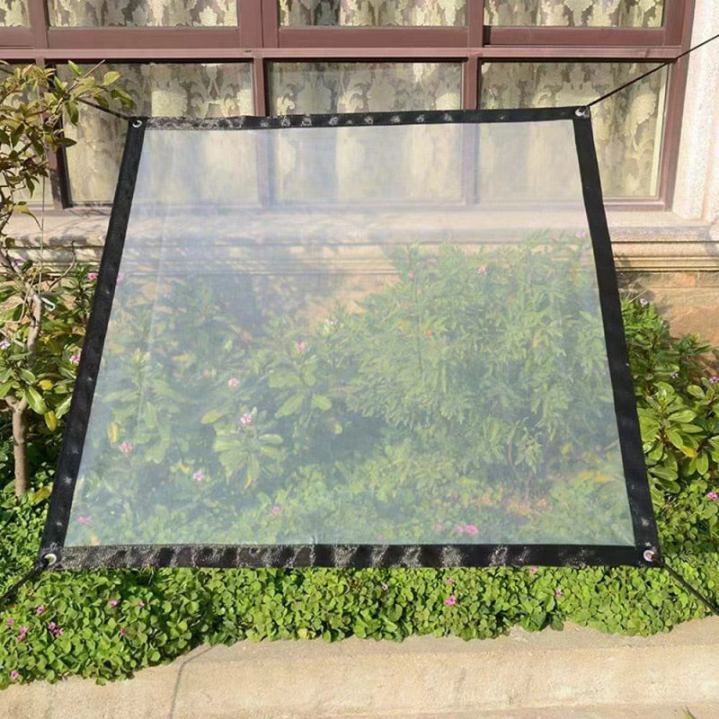 Clear tarp with black border stretched over a flower bed below a window.