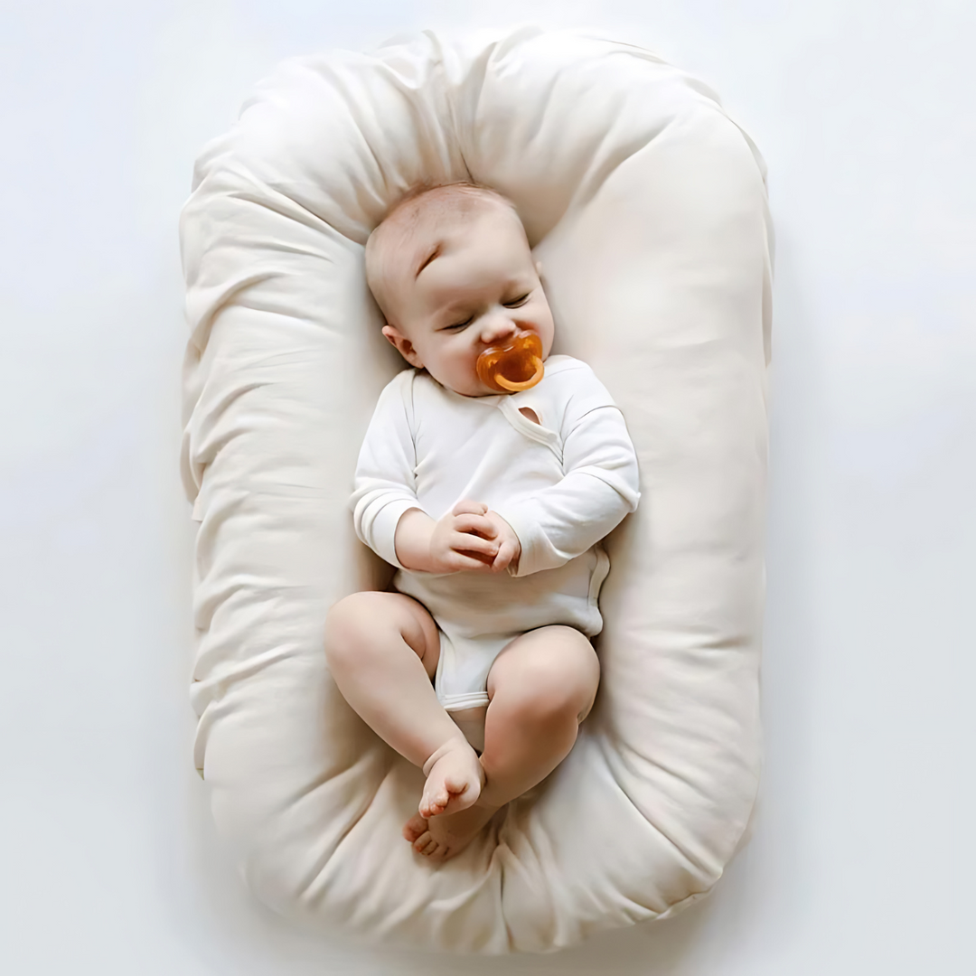 Sleeping baby with an orange pacifier resting in a cream lounger 6