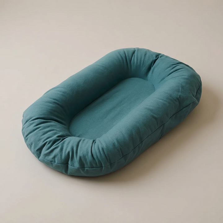 Empty teal oval lounger with raised padded edges, seen from above at an angle 1