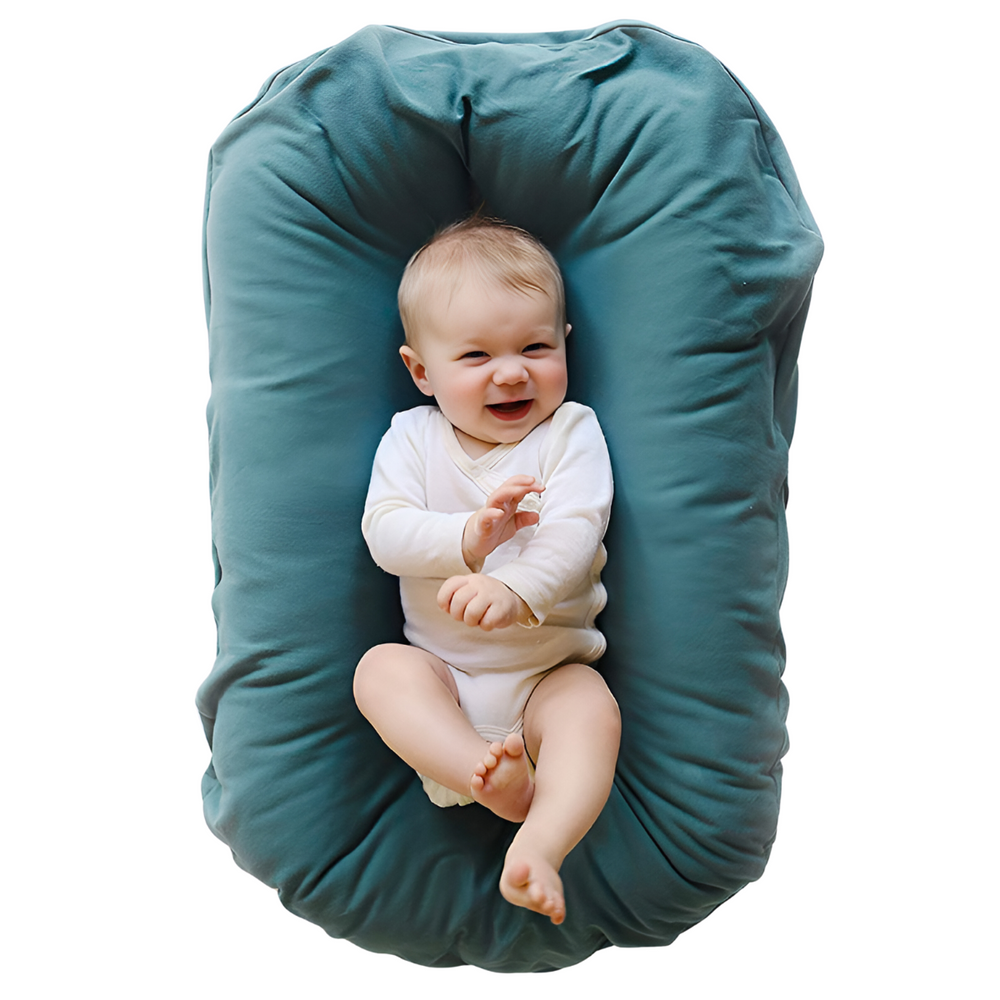 Overhead view of a laughing baby in a white bodysuit lying in a teal lounger 2
