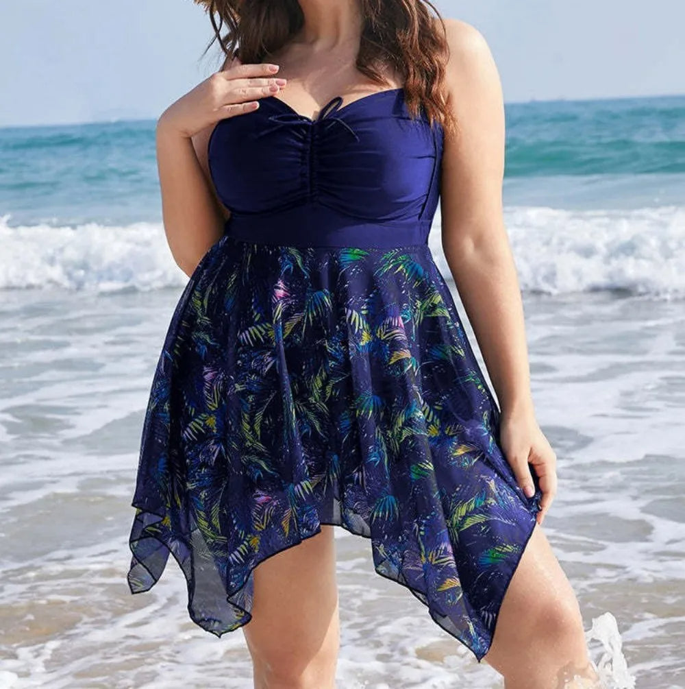 Frau im blauen Badeanzugkleid mit tropischem Muster am Strand, Sommermode, Plus-Size.