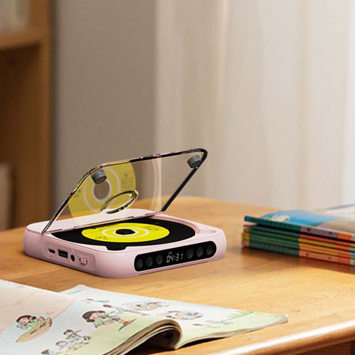 Pink player with open lid on a desk next to a children's book and a stack of books 10