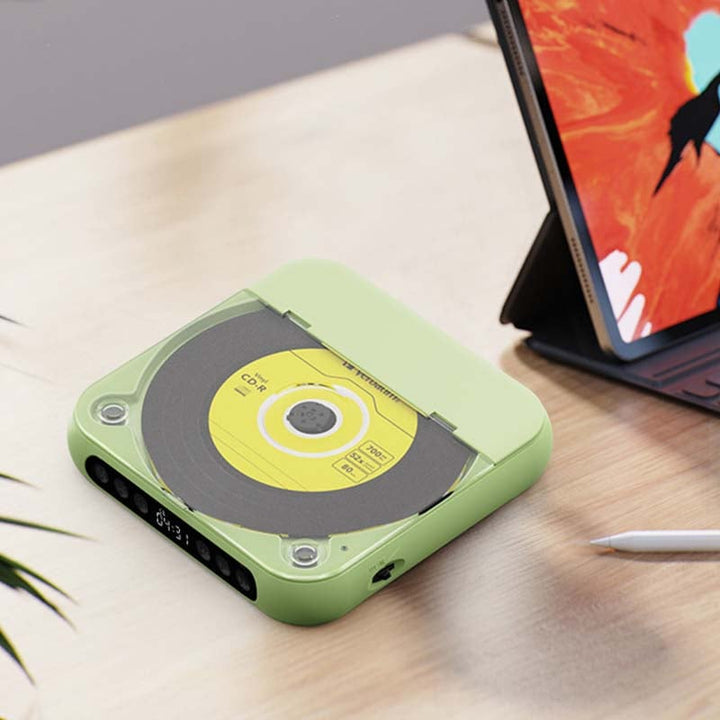 Green player with disc visible under the lid on a light wooden desk next to a tablet and stylus 12