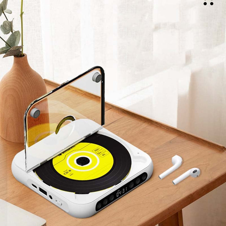 White player with lid raised on a wooden desk beside a vase and a pair of wireless earbuds 8