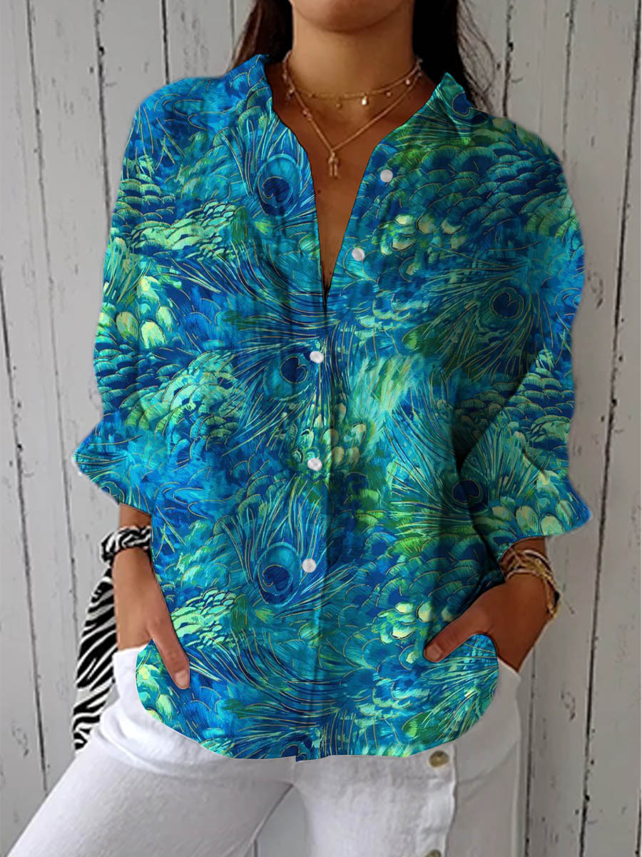 Woman wearing the Peacock Grace Blouse with a blue and green peacock feather print.
