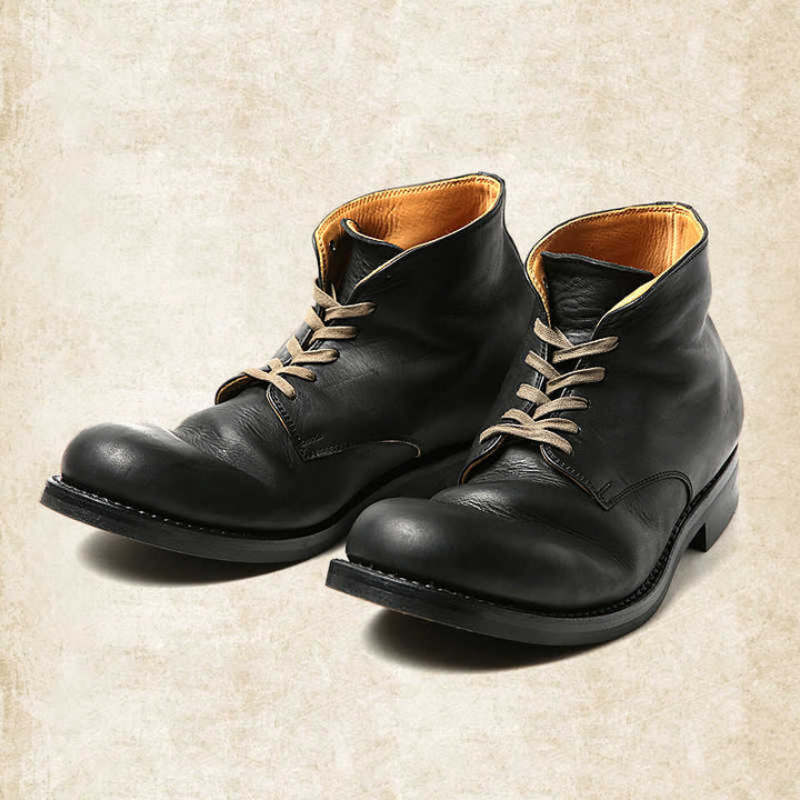 Men's black leather lace-up boots with tan laces and tan lining, detail.