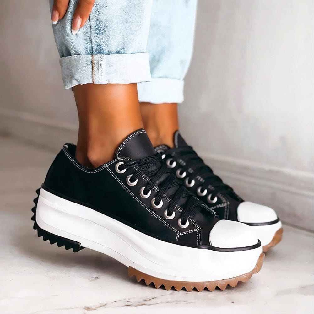 Black lace-up platform sneakers with white contrast stitching, thick white sole and gum rubber tread, worn with rolled light jeans. 3