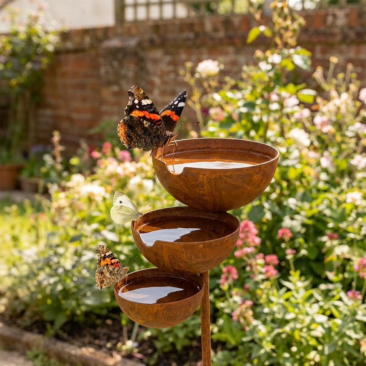 Three-tier bird bath detail showing the rust-toned bowls.