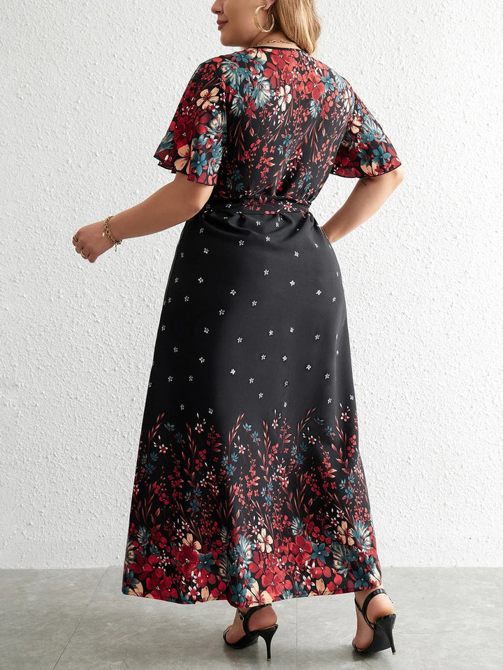 Frau in langem, schwarzem Blumenkleid mit kurzen Ärmeln und roten Blumenmuster, Rückansicht.