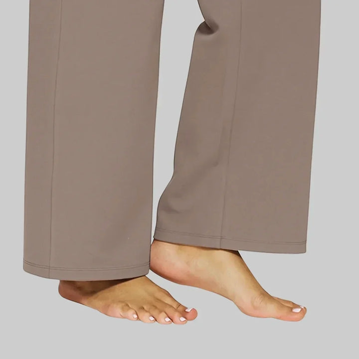 Women's taupe-brown pant hems and seams detail on a model's bare feet, showing the wide straight legs.