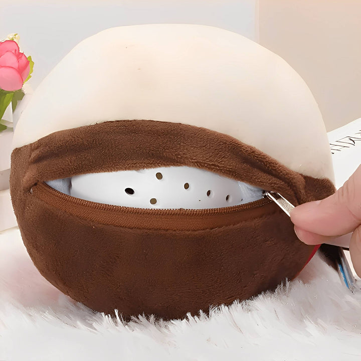 Close-up of a hand unzipping the brown fabric pocket to show the white perforated hard ball inside the plush cover.