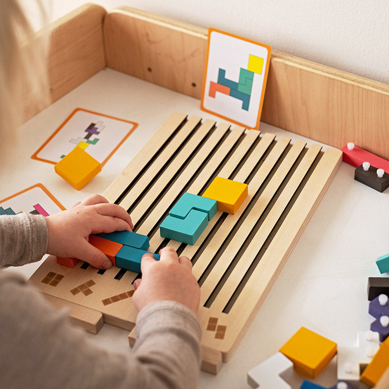 Wooden Tetris puzzle game detail of hands placing blocks into the slotted board