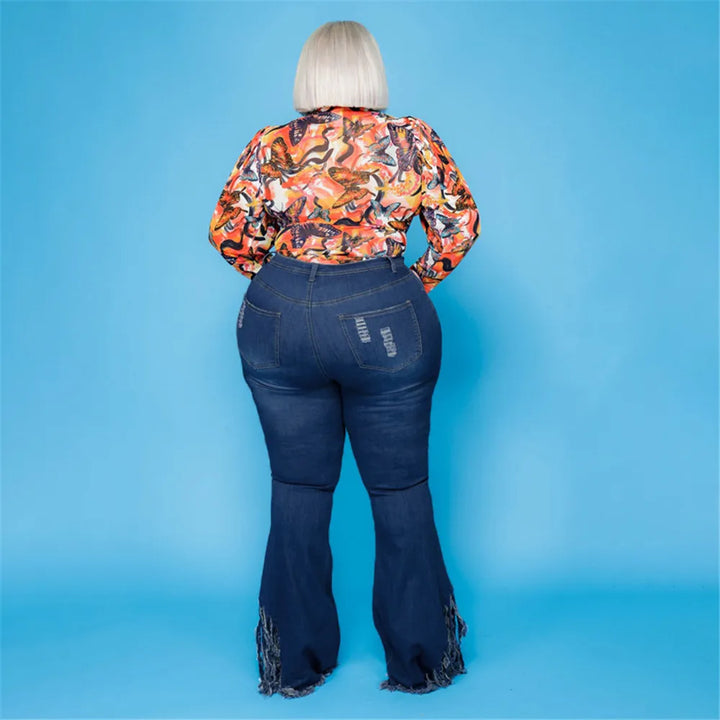 Frau in bunter Bluse und Schlagjeans vor blauem Hintergrund, Mode für große Größen.