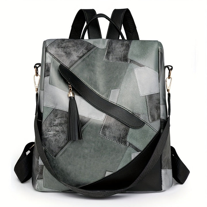 Front view of the gray patchwork backpack with a black diagonal strap, tassel, gold clasps and a removable crossbody strap. 5
