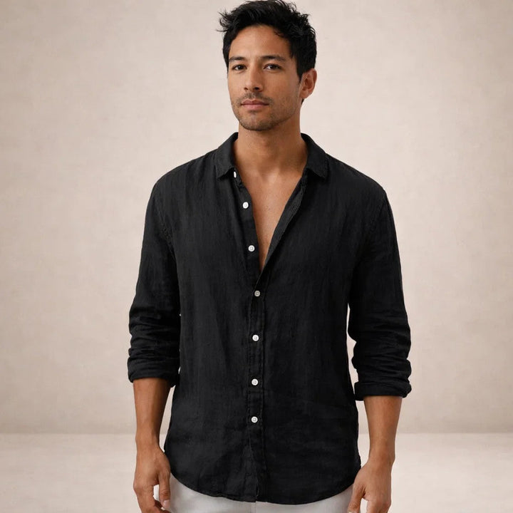 Model looking at the camera in the black linen shirt with rolled sleeves and white buttons, light pants.