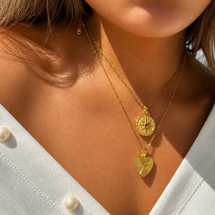Model wearing the star pendant layered with a ribbed heart pendant on a second gold chain 3