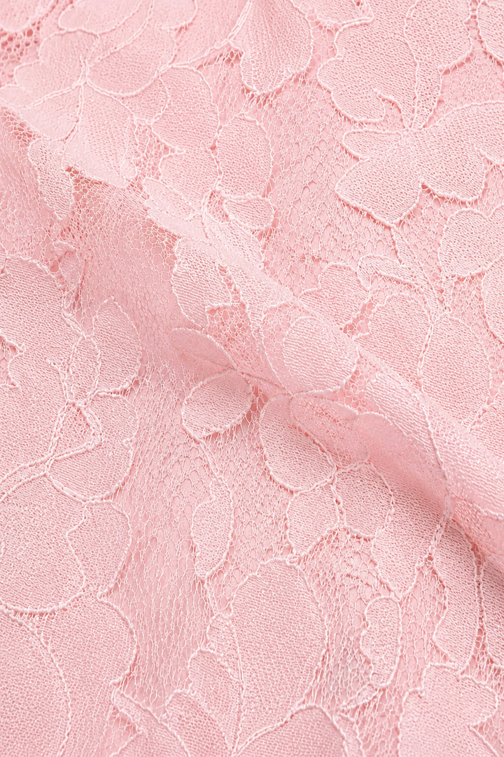 Pink floral lace fabric close-up with a soft fold and delicate net background.