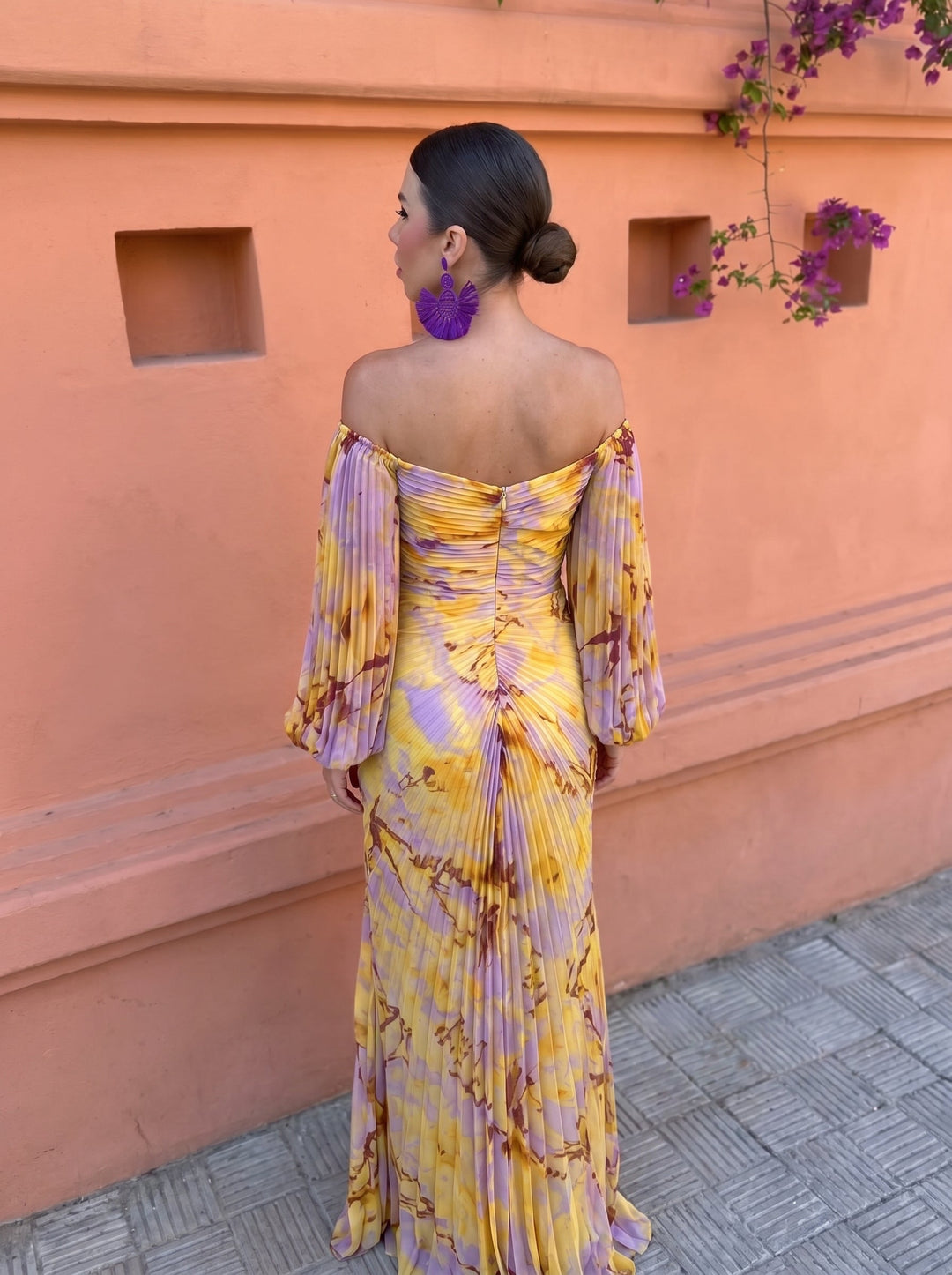 Detail of the back of the long yellow floral dress with an off-shoulder neckline and flowing skirt.