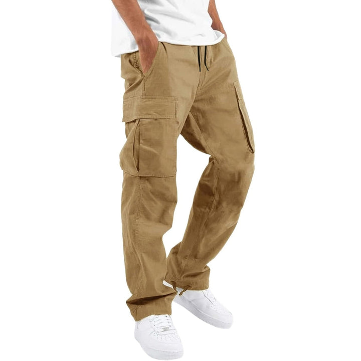 Model wearing tan khaki cargo pants with white tee and white sneakers, hand in pocket, angled side view. 7