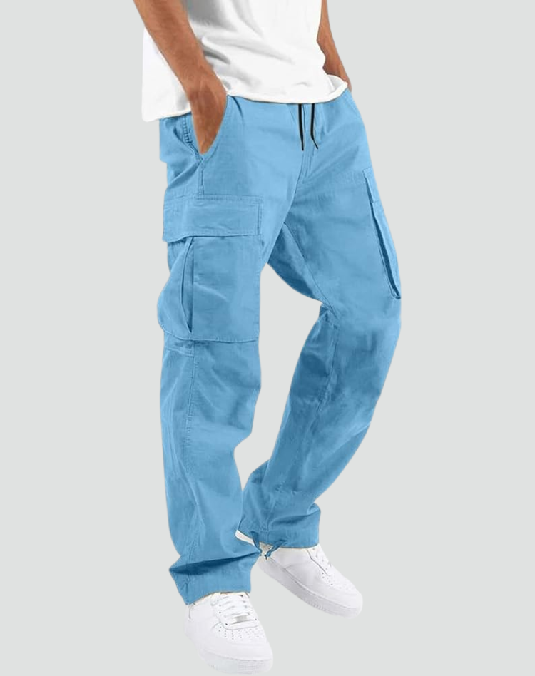 Model wearing light blue cargo pants with white tee and white sneakers, hand in pocket, side view on gray. 14