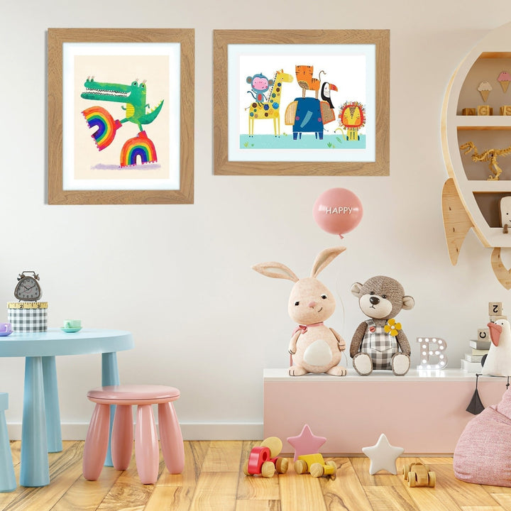 Two wood-tone kids art frames on a nursery wall displaying a crocodile on rainbows and a group of animals.