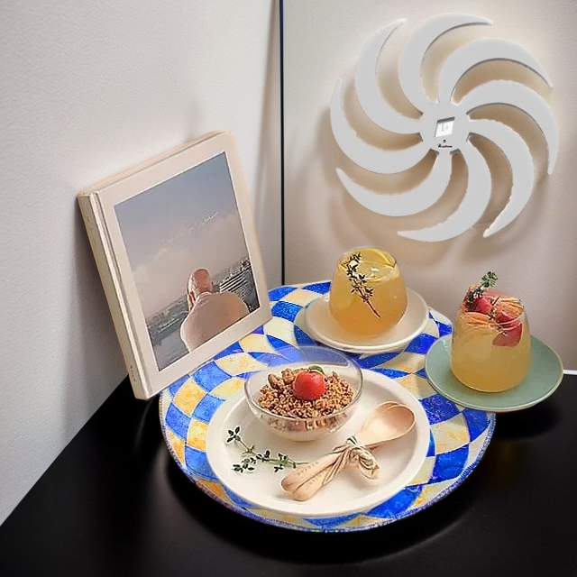 Blue and yellow checkered round placemat holding a granola bowl, two drinks and a book.